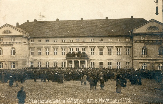 Schwarzweiß Foto: Demonstration am 8. November 1918 auf dem Wismarer Markt, eine Menschenmenge vor dem Rathaus, zwischen Menschen und Fotograf ist noch das Pflaster des Marktes zu sehen.