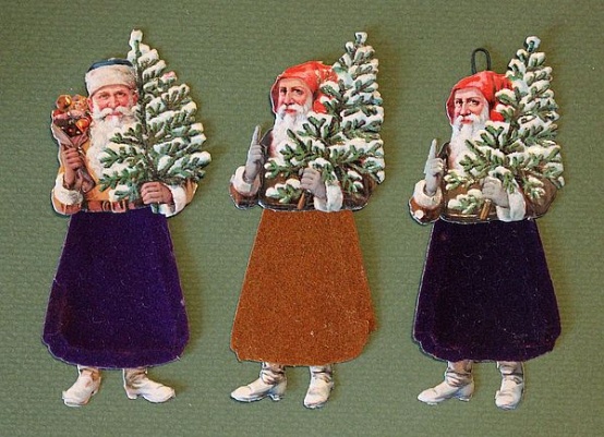 Weihnachtsmänner: im Oberteil und in den Stiefeln als Lackpapier ausgeführt. Sie tragen einen beschneiten Weihnachtsbaum in der Hand. In der einen Ausführung heben sie mahnend den Zeigefinger und in der anderen wird ein Sack mit Äpfeln und Geschenken angedeutet.